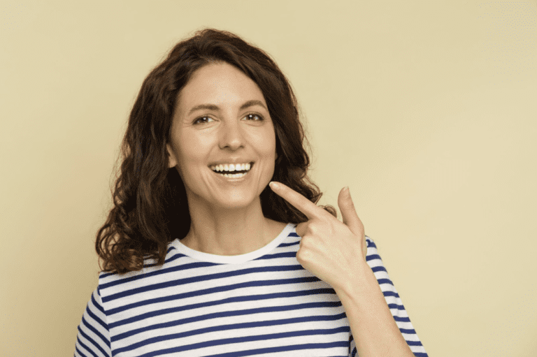 woman smiling and pointing at her teeth